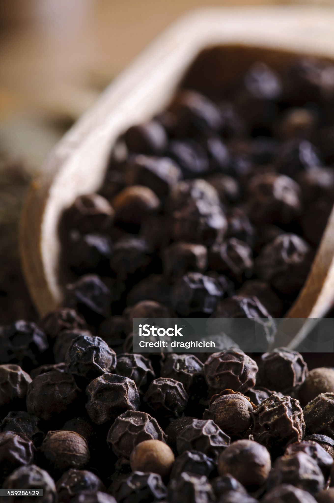 background with close up of black pepper in a wooden spoon